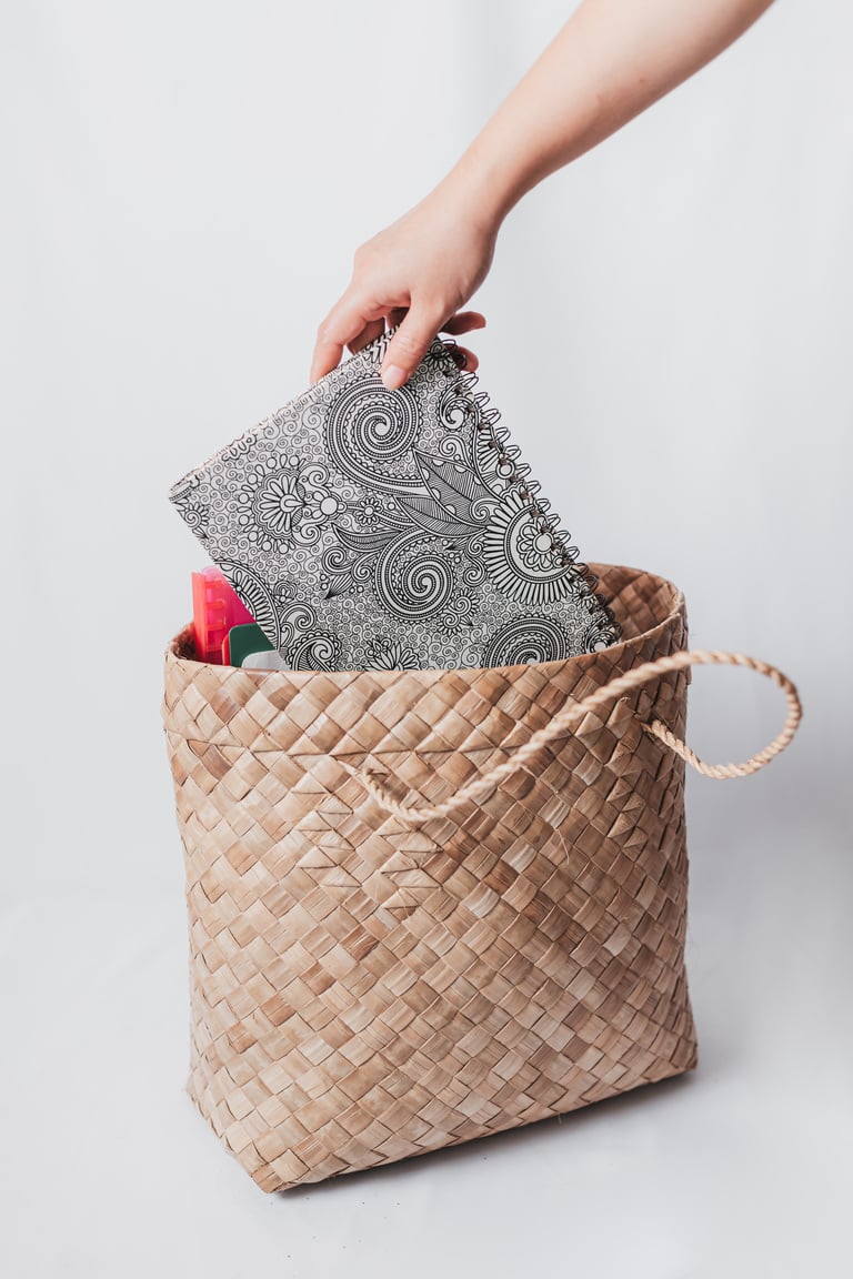 Hand Putting Notebook on Woven Bag